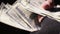 Closeup shot of male hands in shabby fingerless gloves counting cash in dollars