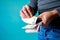 Closeup shot of a male holding a bunch of large Euro bills on a blue background