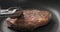 Closeup shot of man hands flip ribeye steak on non stick pan with steel tongs