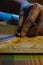 Closeup shot of a man\'s hand cutting a garlic clove with knife on a wooden board