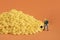 Closeup shot of miniature labor figures on a pile of corn on orange background