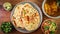 Closeup shot of naan flatbreads, lime, greens, salad, soup on a wooden table