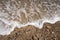 Closeup shot of the ocean meeting a part of the shore with sand and small rocks and pebbles