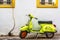 Closeup shot of an old green moped in front of the white wall