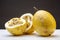 Closeup shot of one full and two halves of yellow passion fruit on a white surface