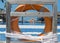 Closeup shot of an orange lifebuoy tied on a wooden piece near an open-air swimming pool