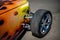 Closeup shot of an orange vehicle wheel with a black tire parked on asphalt