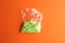 Closeup shot of packaged green round confetti on an orange background