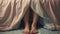 closeup shot of person feet under blanket in bedroom