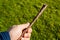Closeup shot of a person holding a stick of wood over the grass covered field