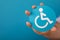 Closeup shot of a person holding a wheelchair Symbol against a blue background