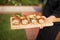 Closeup shot of a person holding a wooden board with shrimp rolls on it at a private event