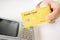 Closeup shot of a person holding a yellow credit card with a payment terminal on a white table