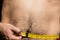 Closeup shot of a person measuring his waist with a measuring tape