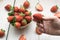 Closeup shot of a person picking a fresh strawberry from a straw bowl on a wooden surface