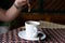 Closeup shot person pouring brown sugar on a cup of coffee