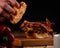 Closeup shot of a person putting the bread on a delicious hamburger on a wooden board