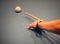 Closeup shot of a person& x27;s hand aiming on a white snooker ball with a cue. Billiard concept.
