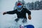 Closeup shot of a person in snowboarding gear going down a snow slope on a snowboard