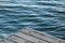 Closeup shot of a piece of wooden pier and wavy blue ocean