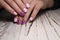 Closeup shot of pink manicure of female's short nails with purple patterns