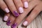 Closeup shot of pink manicure of female's short nails with purple patterns