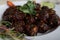 Closeup shot of a plate of roasted meat decorated with green groceries on a wooden table