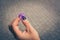 Closeup shot of a purple flower in the hands of a woman over the tiles of the ground