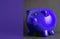 Closeup shot of a purple piggy bank on a gray background with a purple part for copy space