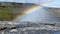 Closeup shot of a rainbow spanning from a waterfall base in a mountainous area