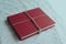 Closeup shot of a red book wrapped with brown thread on a marble surface