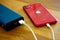 Closeup shot of a red iPhone 11 being charged by a power bank on the wooden table