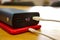 Closeup shot of a red iPhone 11 being charged by a power bank on the wooden table