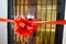 Closeup shot of a red ribbon with a bow in front of a wooden door with glass windows