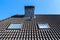 Closeup shot of a roof in Velux style with black tiles on a blue sky background