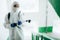 Closeup shot of a sanitary professional worker wearing protective suit disinfecting a staircase entryway block of flats.