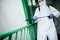 Closeup shot of a sanitary professional worker wearing protective suit disinfecting a staircase entryway block of flats.