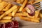 Closeup shot of a sausage piece on the fork with fries in the background