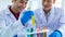 Closeup shot of scientist student hand in blue rubber gloves holding yellow solvent in glass test tube from colorful sample rack