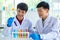 Closeup shot of scientist student hand in blue rubber gloves holding yellow solvent in glass test tube from colorful sample rack