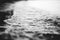 Closeup shot of the sea waves coming up to the shore with blurred background in black and white