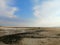 Closeup shot of a shore with beautiful sand under the sunlight and a person visible from far