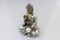 Closeup shot of a silver Buddha statuette on a white surface