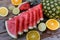 Closeup shot of sliced watermelon, oranges, lime and pineapple on a wooden surface