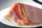 Closeup shot of slices of delicious ham on a white plate