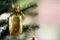 Closeup shot of small lovely seasonal festival decorative bright shiny golden bag hanging on Christmas green pine tree on x-mas