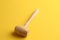 Closeup shot of a small wooden mallet isolated on a yellow background