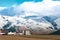 Closeup shot of snowy rugged landscape of the mountains with small houses and factory in a field