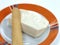 Closeup shot of soft cheese of bovine stracchino on a plate on a white isolated background