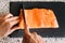 Closeup shot of someone cutting the delicious salmon into pieces on a black board